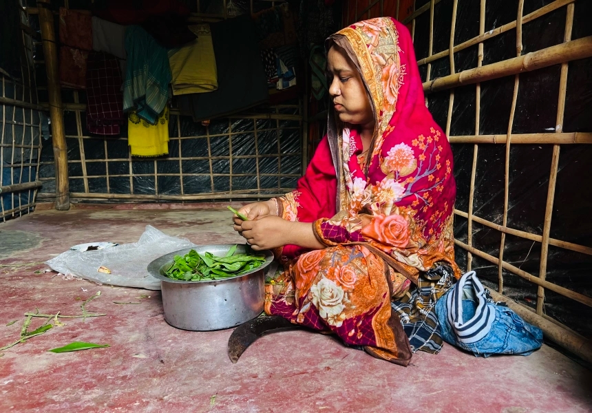 Jasmin Ara, a Rohingya woman living in a refugee camp, preparing dinner for her children with limited supplies.
